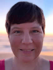 Close up portrait of a woman with short brown hair smiling at the camera.