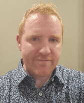 Portrait of a man with short red hair wearing a blue shirt with white paisley pattern.