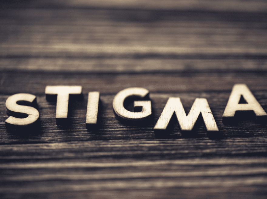 Wooden letters spelling 'Stigma' on a dark wooden surface, symbolizing the concept of stigma related to social issues like substance use and criminal-legal involvement.