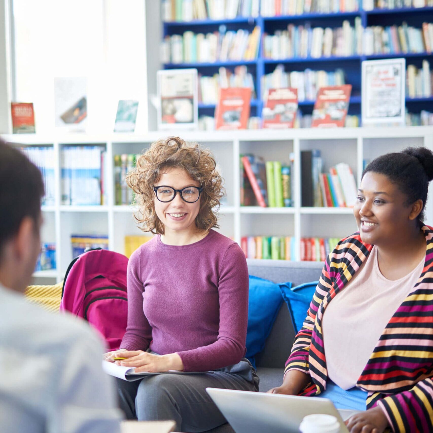 Group of students working together while sitting on a sofa in a library.