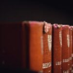 Cropped view of the tops of books in a column against a black background.